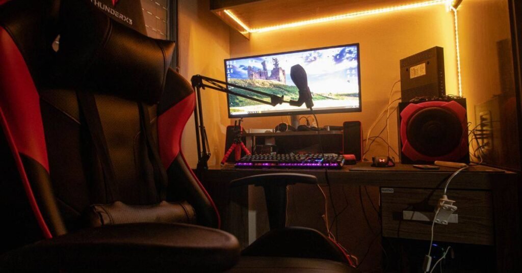 RGB gaming setup with monitor, microphone, and gaming chair in warm lighting