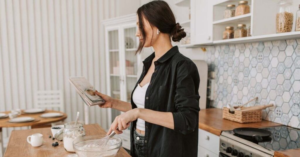Woman reading recipe while mixing batter in kitchen