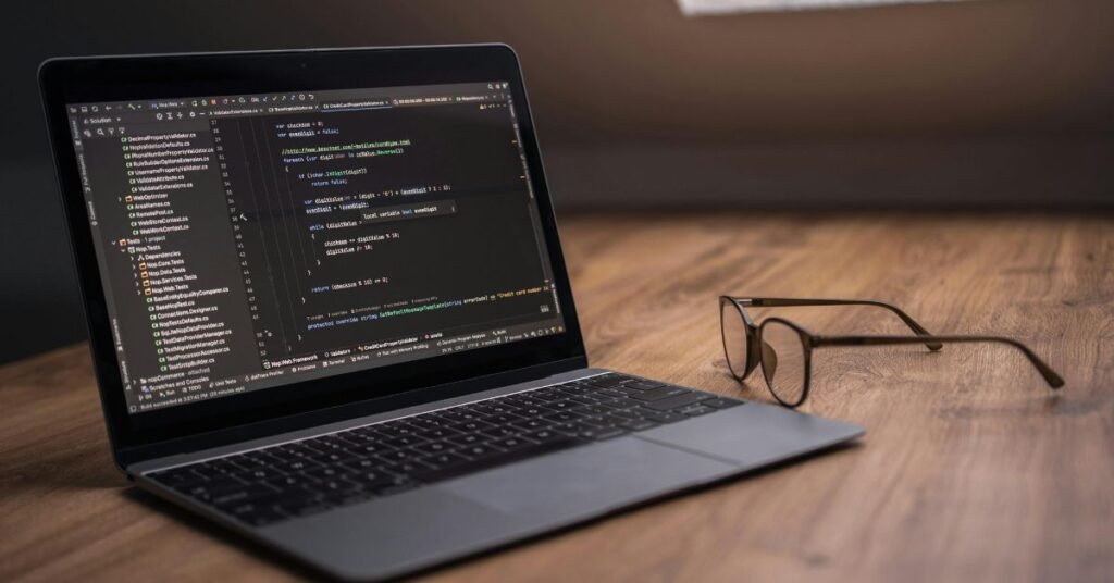 Laptop with coding screen and glasses on desk